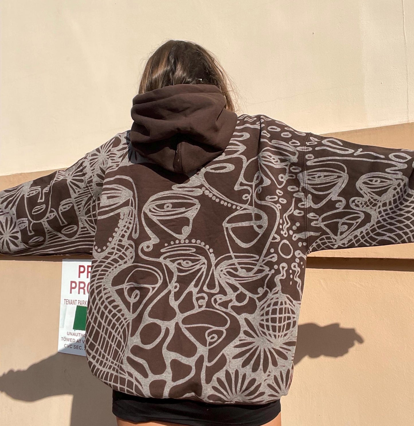 Abstract faces, spiral geometric pattern, and celestial sun print style hoodie in golden tan/yellow and white/ cream