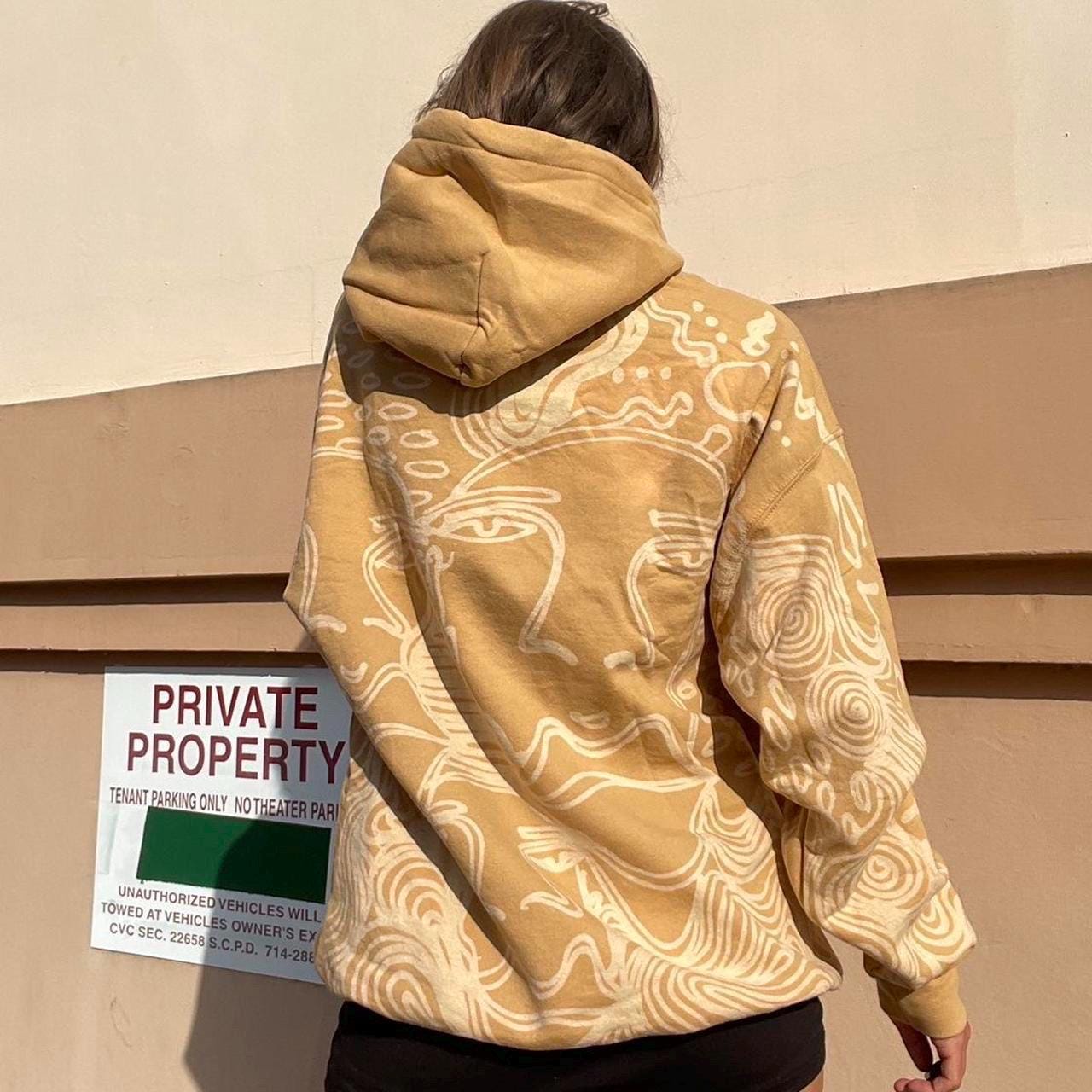 Abstract faces, spiral geometric pattern, and celestial sun print style hoodie in golden tan/yellow and white/ cream