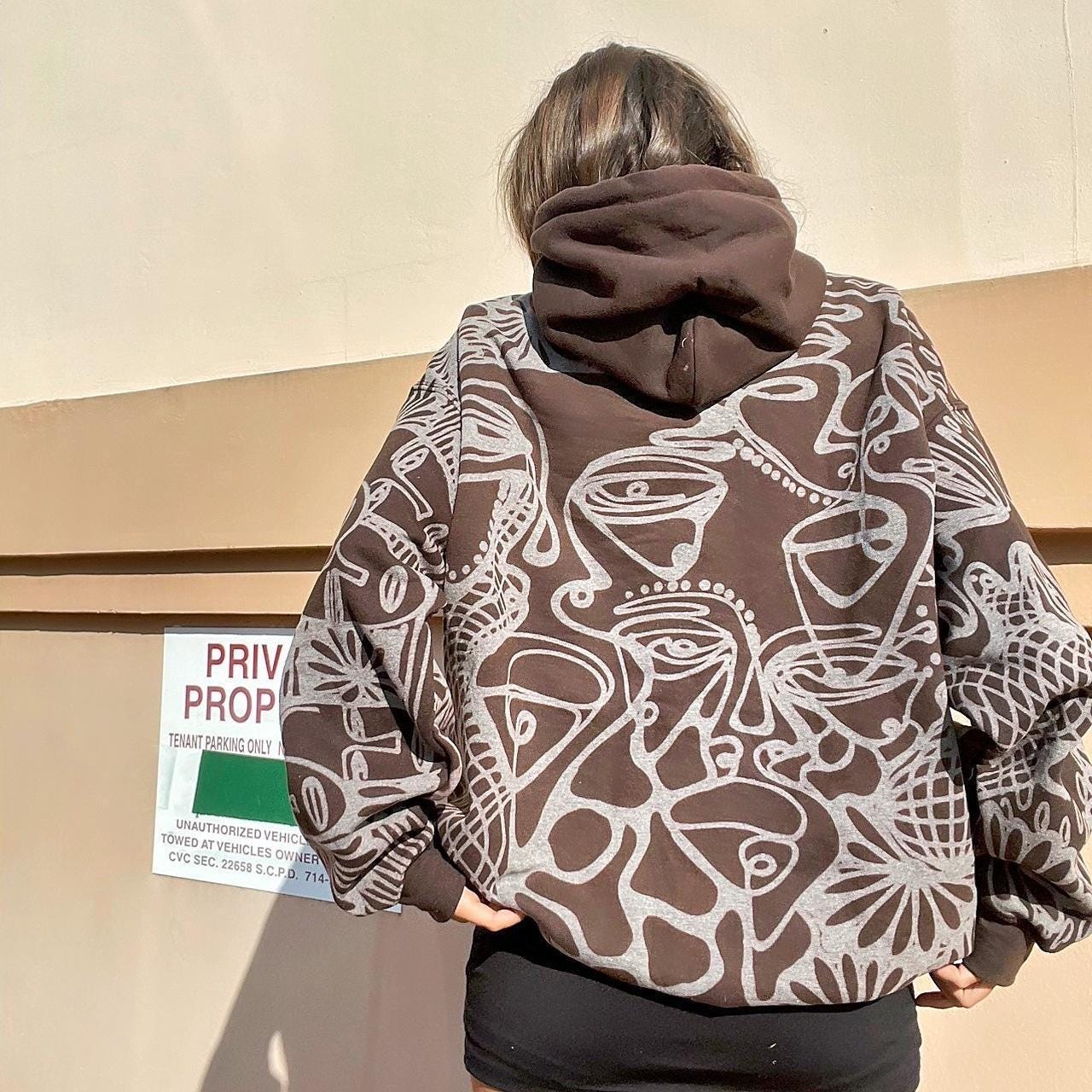 Abstract faces, floral pattern, and geometric style hoodie in dark chocolate brown and cream